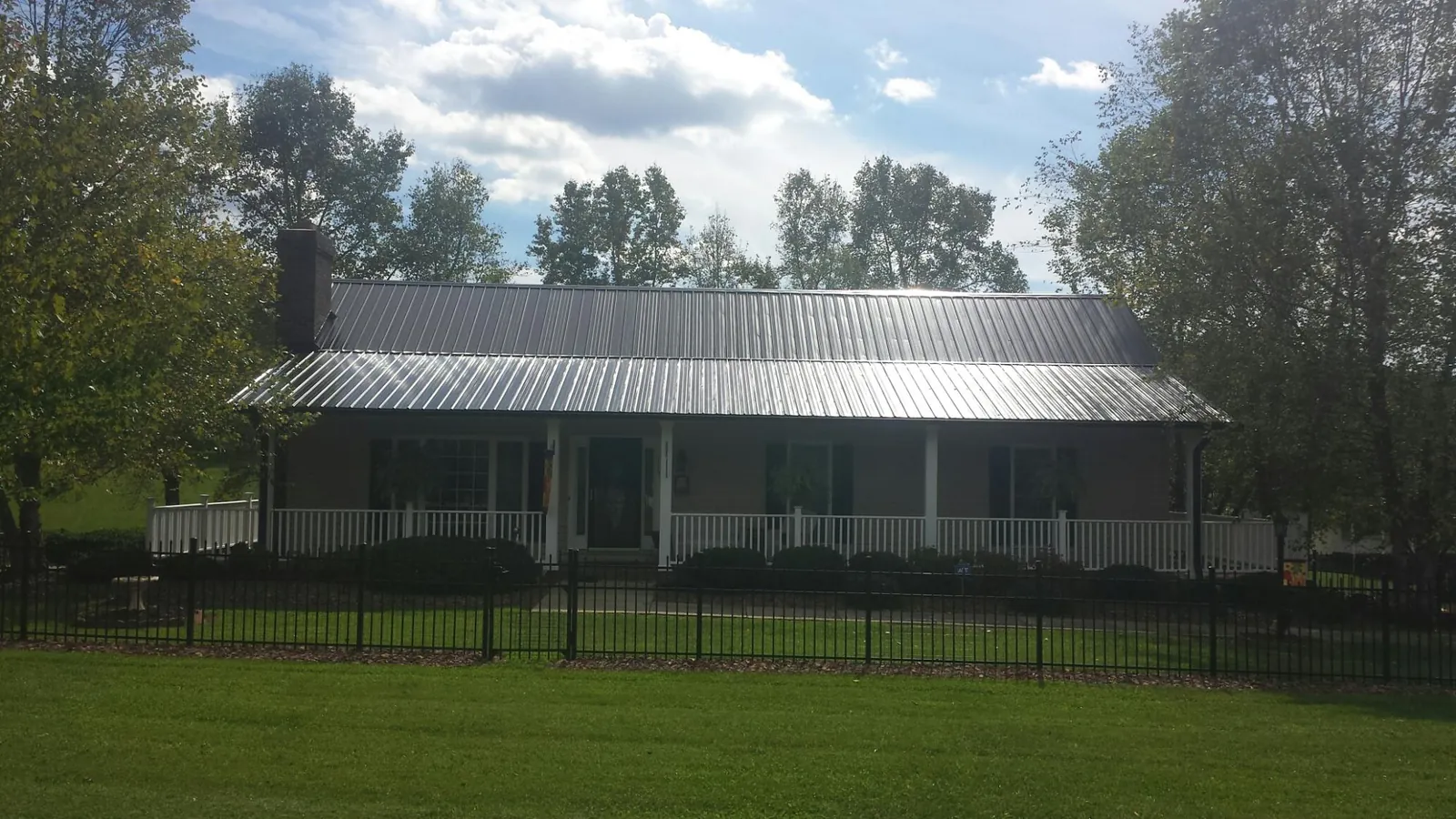Gray metal roof on a brick ranch with a full width front porch — Gutter Guard Installation work by our crew in Dwight