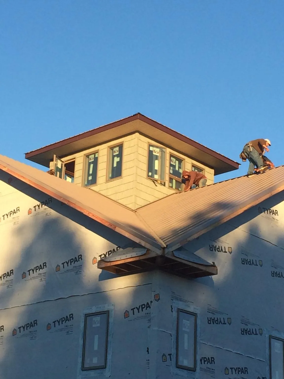 Roofers working around a rooftop cupola on a new metal roof at sunset — Roof Waterproofing in Dwight by Roofing Brothers